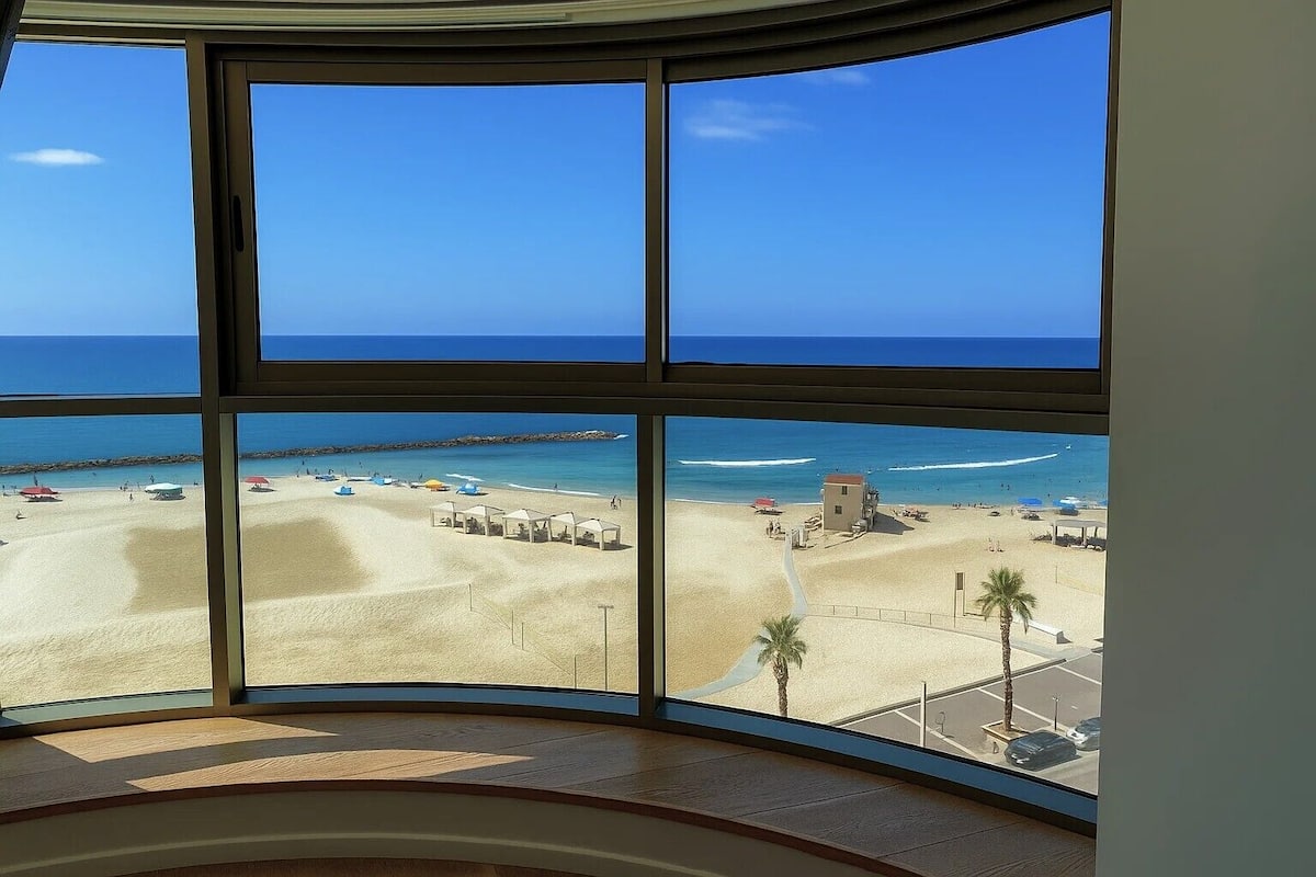 Vista panorámica de una playa desde una habitación con ventanas amplias.