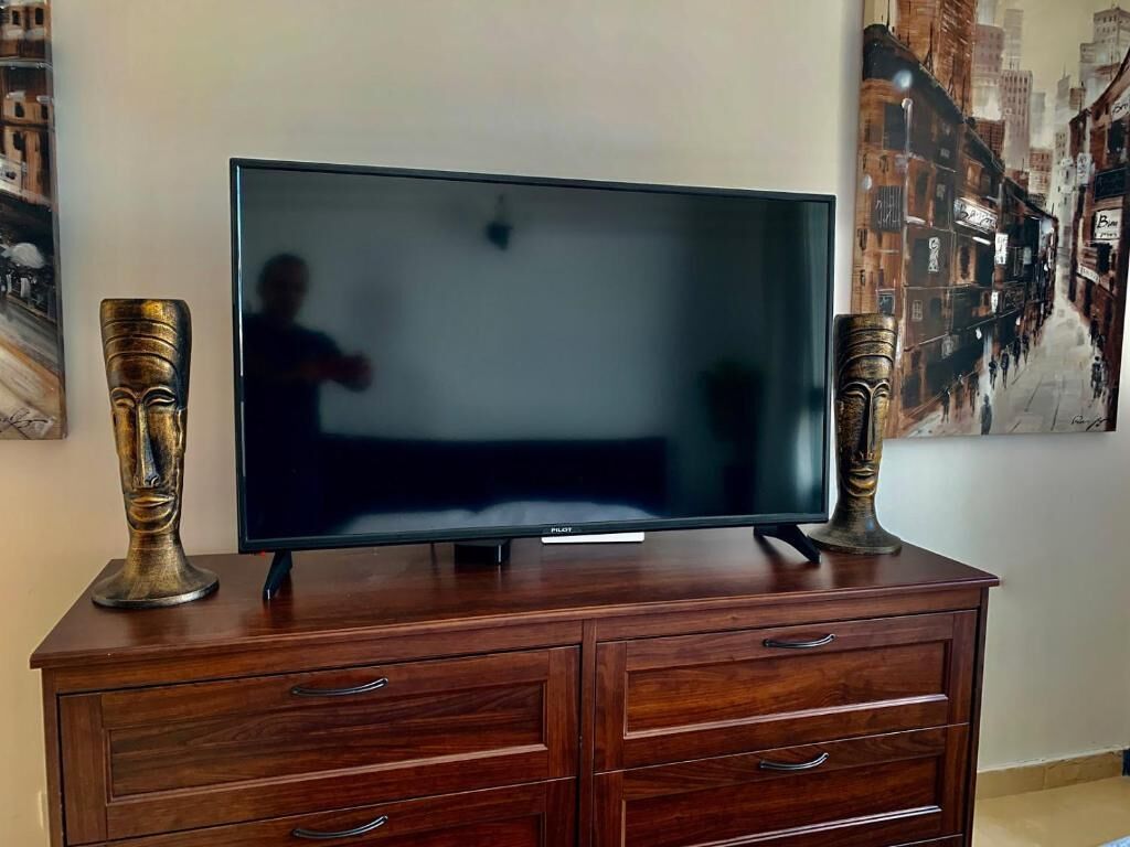 Un televisor de pantalla plana sobre un mueble de madera con dos jarrones decorativos a cada lado.