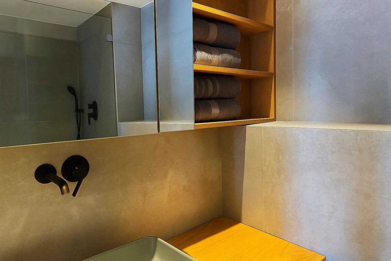 Un baño moderno con ducha integrada, estante de madera con toallas y diseño minimalista.