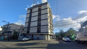 Un immeuble à plusieurs étages doté de balcons, une voiture garée et une moto devant.
