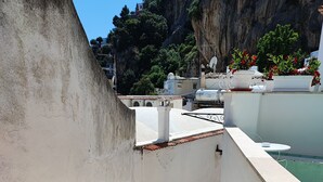 Eine Dachterrasse mit Blick auf einen felsigen Hang und ein Gebäude im Hintergrund.