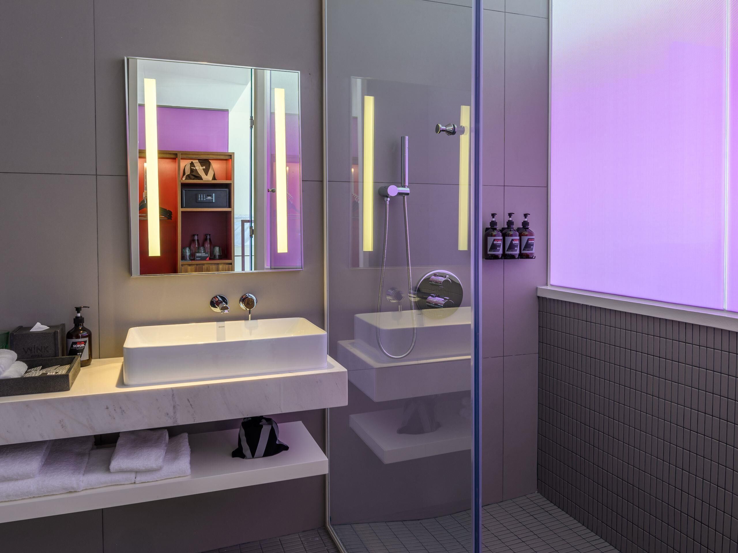 Ein modernes Badezimmer mit Duschkabine aus Glas, Waschtisch mit Spiegel und Ablage für Toilettenartikel.