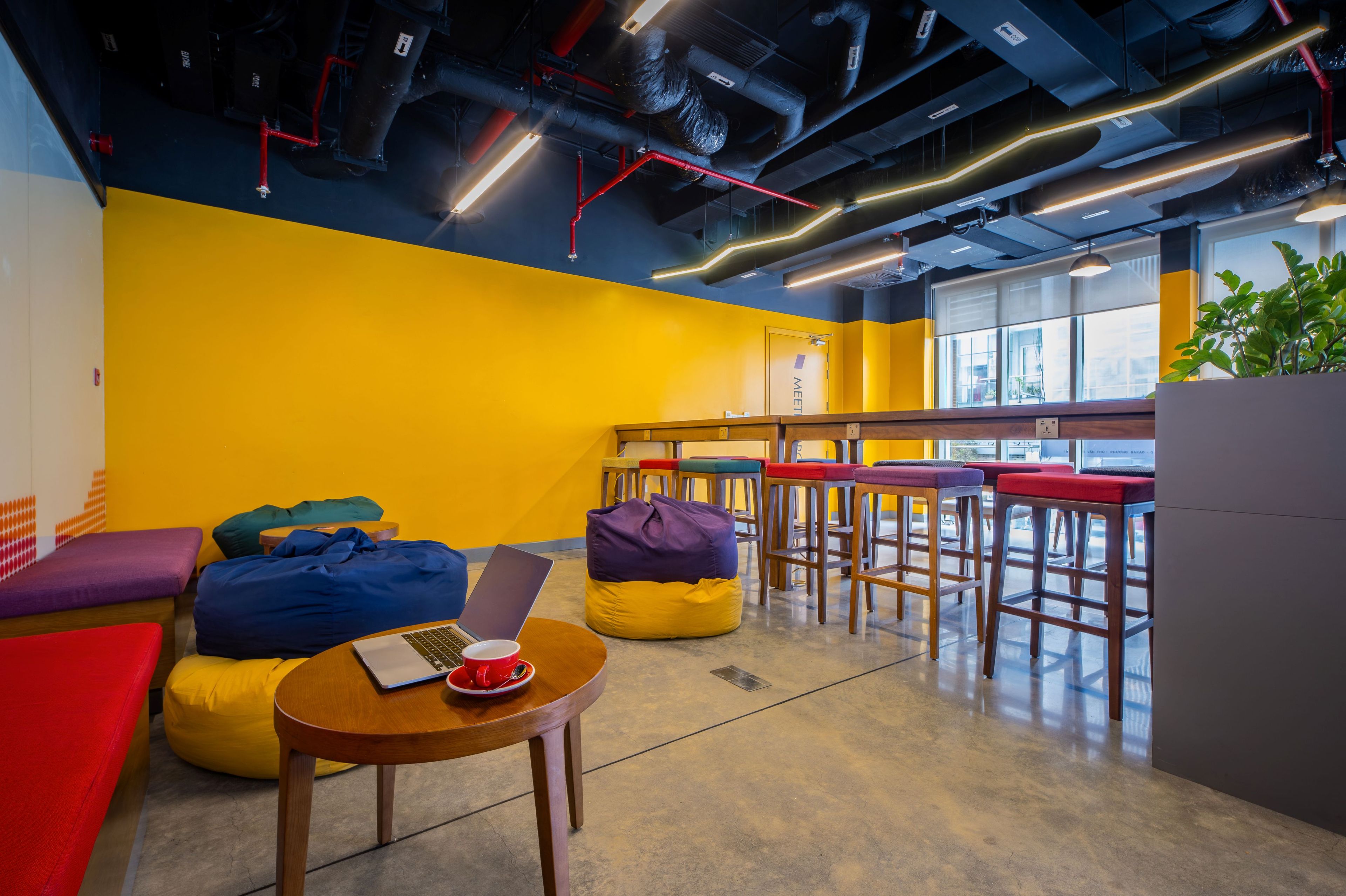 A modern lounge area with colorful seating, a coffee table, and a laptop.