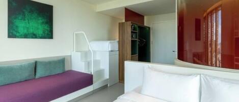 Ein modernes Hotelzimmer mit Bett, Sofa, Treppe und Kleiderschrank.