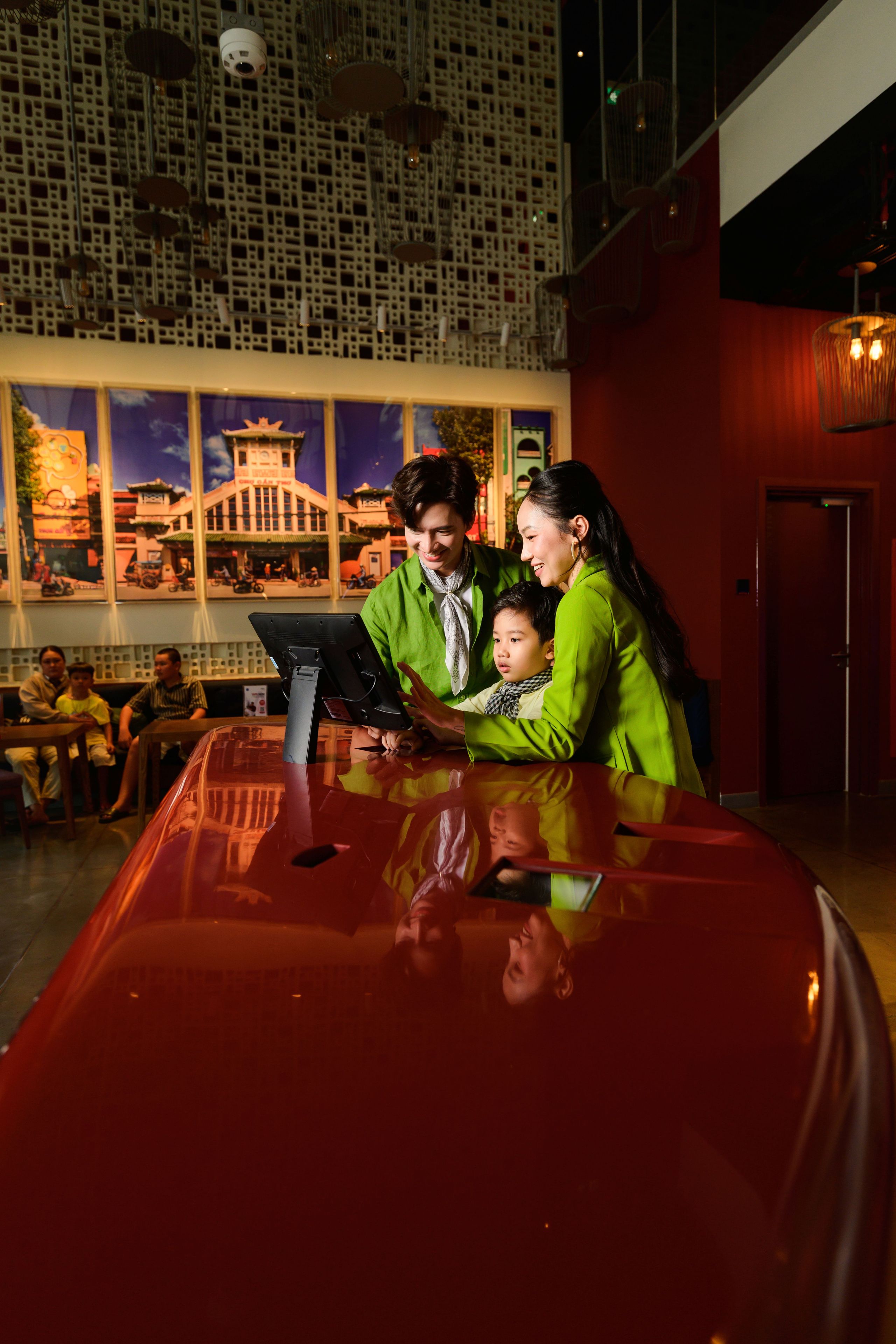 A family interacting with a digital kiosk in a modern lobby with a large window displaying a cityscape.