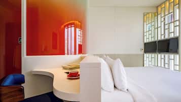 A hotel room with a bed, a desk, a chair, and a window with a view.