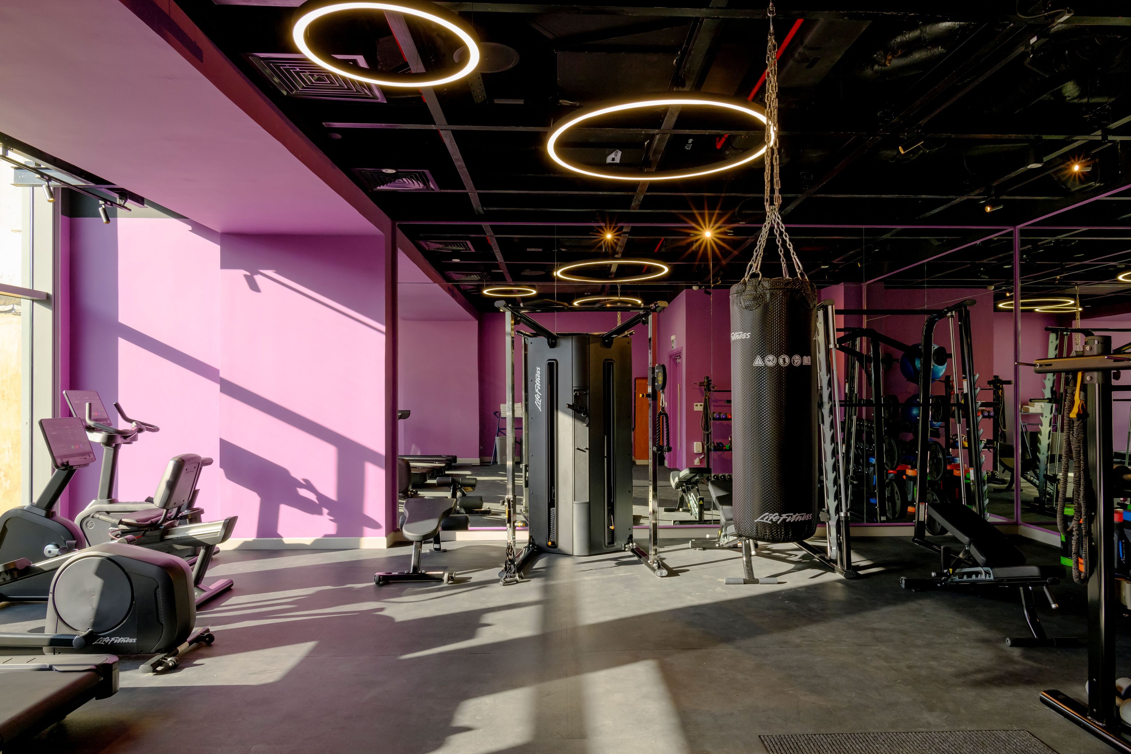 A gym with exercise equipment, a punching bag, and a mirror.