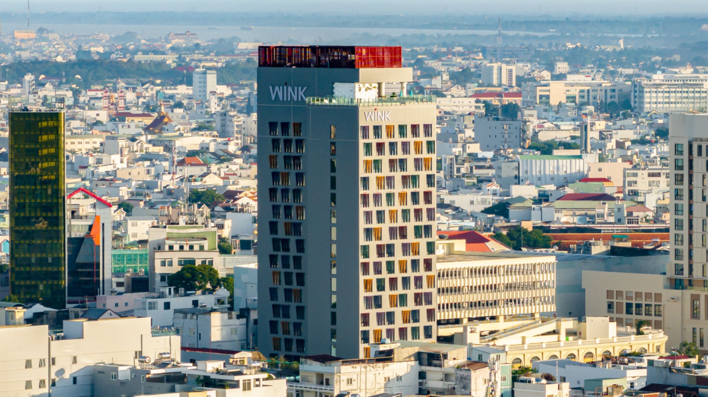 Un grattacielo con numerose finestre e balconi, immerso in una zona urbana densamente popolata da diversi edifici.