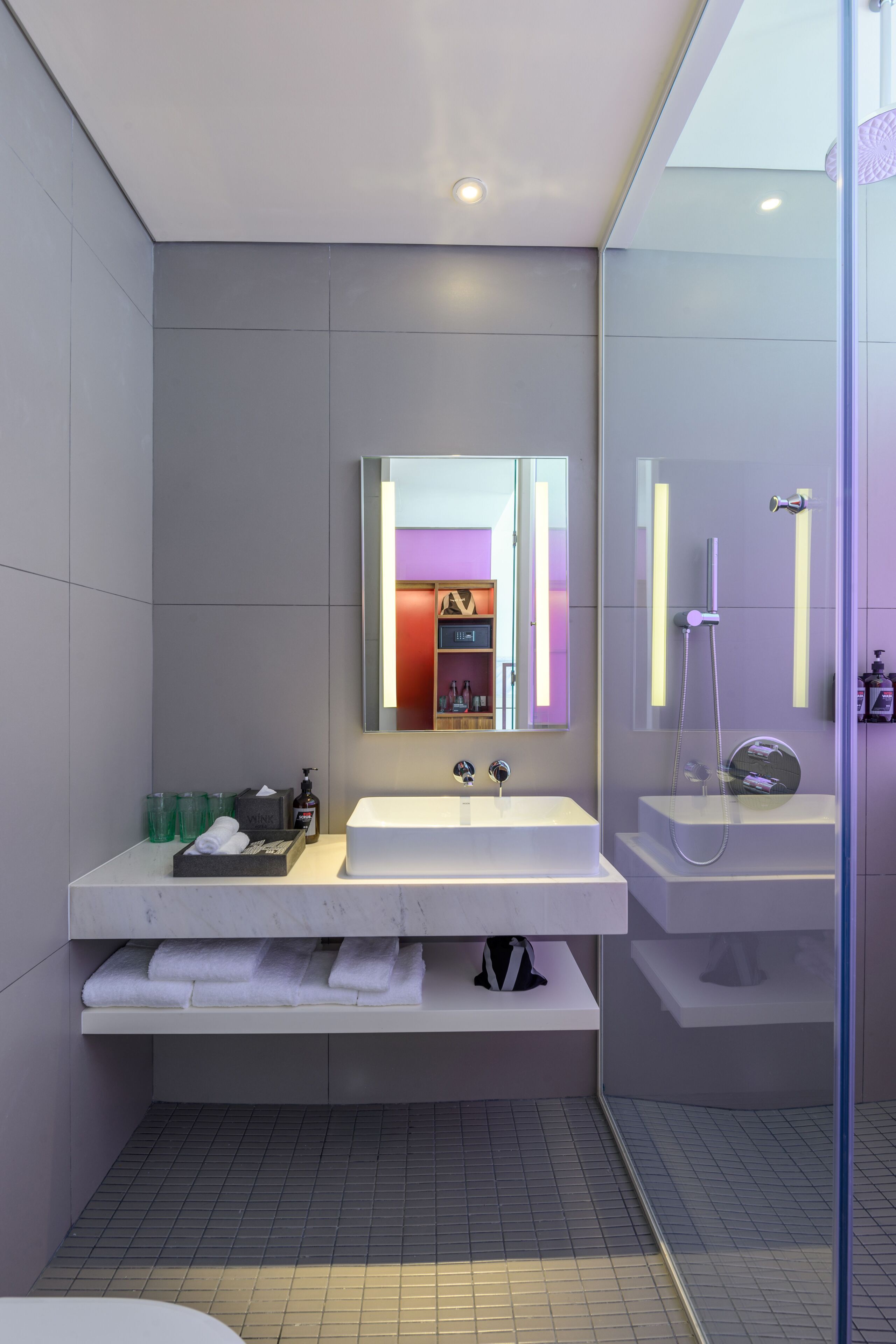 A modern bathroom with two sinks, a large mirror, and a glass-enclosed shower.