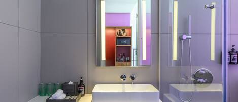 Un baño moderno con dos lavamanos, un espejo grande y una ducha con mampara de vidrio.