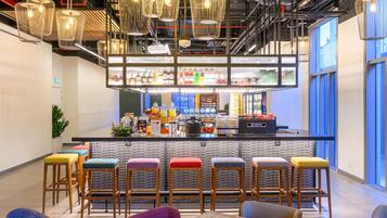 Uma área de bar moderna com banquetas, balcão e luminárias pendentes.