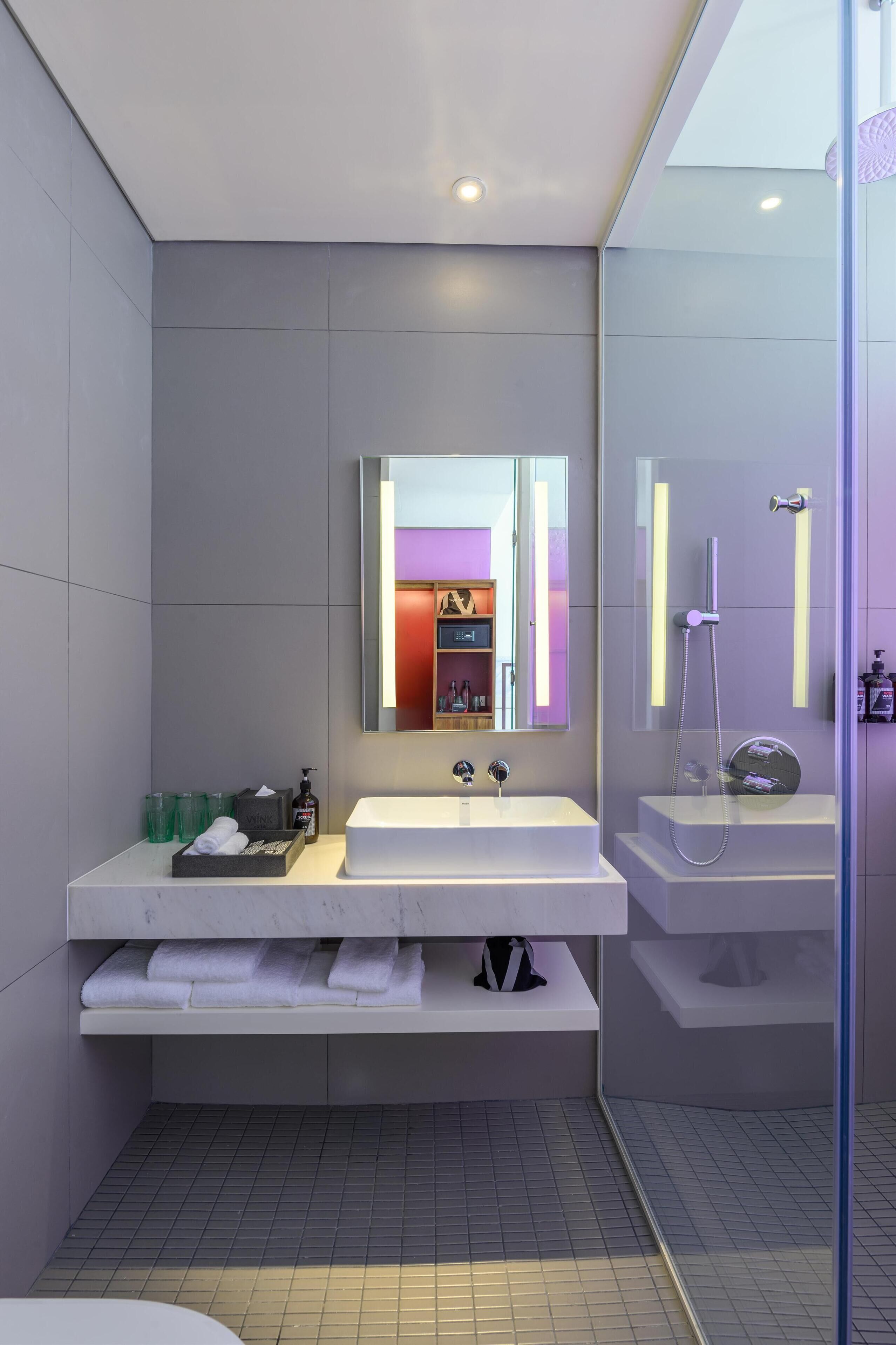 Une salle de bain moderne avec deux lavabos, un grand miroir et un espace douche.