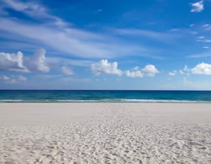 Une plage avec un ciel dégagé et une mer calme.