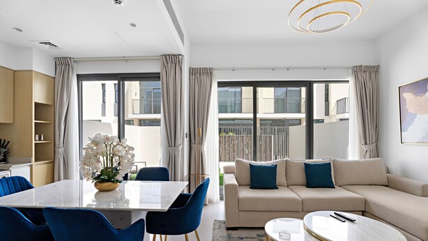 Un salon moderne comprenant un canapé, une table basse et un coin repas avec des chaises.