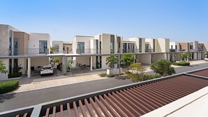 Un complexe résidentiel moderne composé de plusieurs bâtiments à deux étages, doté d’un parking couvert et de petits espaces paysagers.