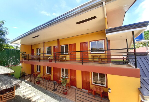 A two-story building with balconies, potted plants, and outdoor seating. - SUMMER WIND PENSION (Puerto Princesa)