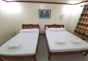 Two single beds with white linens and wooden headboards in a room with a plain white wall and a framed picture. - SUMMER WIND PENSION (Puerto Princesa)