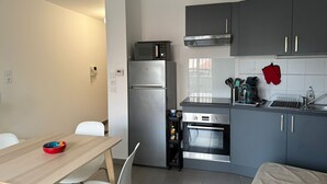 Et lille køkken med køleskab, mikroovn, ovn og moderne skabe.