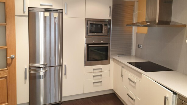 A modern kitchen with stainless steel appliances, including a refrigerator, microwave, and oven, and white cabinetry.