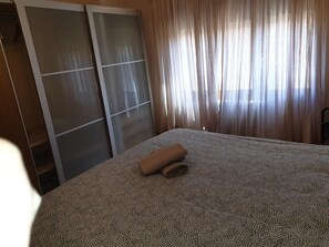 A room with a bed, a wardrobe, and a window with curtains. - Spacious 3-Bedroom Apartment in Central Jaca with Parking and Modern Amenities (Jaca)