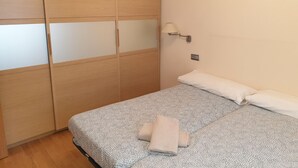 A bedroom with a bed, a wardrobe, a nightstand, and a wall-mounted lamp.