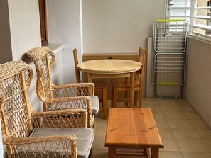 Cozy room with a round table and four chairs, a wooden stool, and a window with a drying rack.