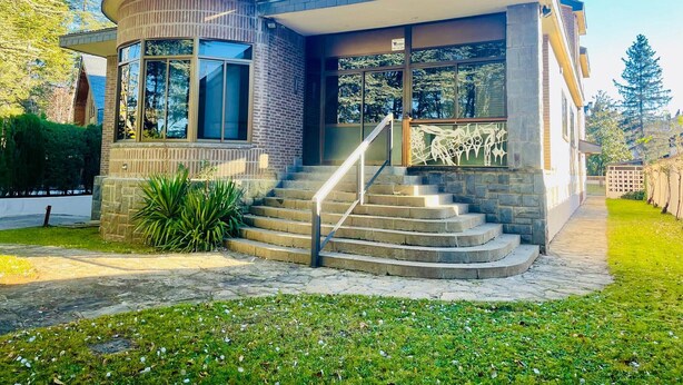 Una casa moderna con fachada curva, ventanas amplias y una escalera de piedra que conduce a la entrada.