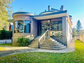 A modern house with a curved facade, large windows, and a stone staircase leading to the entrance. - Spacious Villa in Jaca with Private Pool and Garden (Jaca)