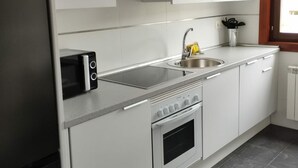 Una cocina moderna con armarios blancos, un lavamanos de acero inoxidable, un horno empotrado y un tostador.