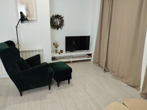 Relax in this stylish living room with a comfortable armchair, matching ottoman, and flat-screen TV.