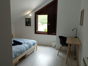Cozy bedroom with a single bed and desk, offering a view of the outdoors.