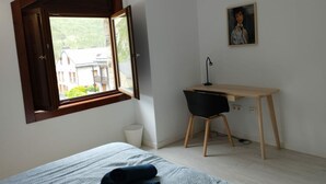 Un dormitorio con cama, escritorio y ventana.