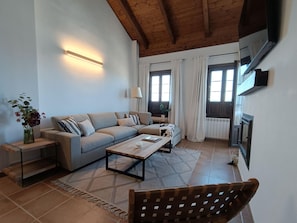 A living room with a sofa, coffee table, lamp, and a TV mounted on the wall.