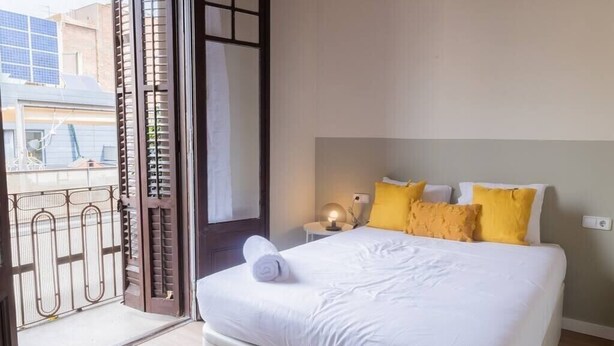 Un dormitorio con cama, mesita de noche y ventana con persianas.