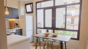 Une cuisine compacte avec un coin repas, de grandes fenêtres et une vue sur le balcon extérieur.