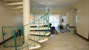 Un escalier en colimaçon avec des rampes vertes et des marches en marbre, menant à l’étage supérieur.