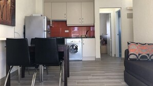 A compact living space with a dining area, kitchenette, and a sofa. - Denia: Appartement 1 Chambre avec Piscine, Clim et Parking à 500m de la Plage (Denia)