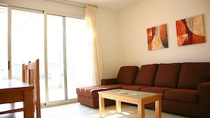 A living room with a sofa, a coffee table, and a dining area with chairs. There are two abstract paintings on the wall. - Semi-detached house in Creixell with pool and WIFI, near beach (Creixell)
