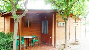 A wooden cabin with a covered patio, a door, and a window.