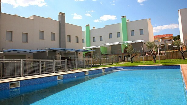 A swimming pool with a tiled edge, surrounded by a fenced area with a metal gate. - Semi-detached houses in Creixell with pool, WiFi, parking, and air conditioning (Creixell)