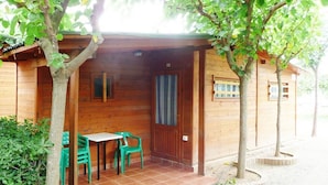 Una cabaña de madera con un porche cubierto, una puerta y una ventana.