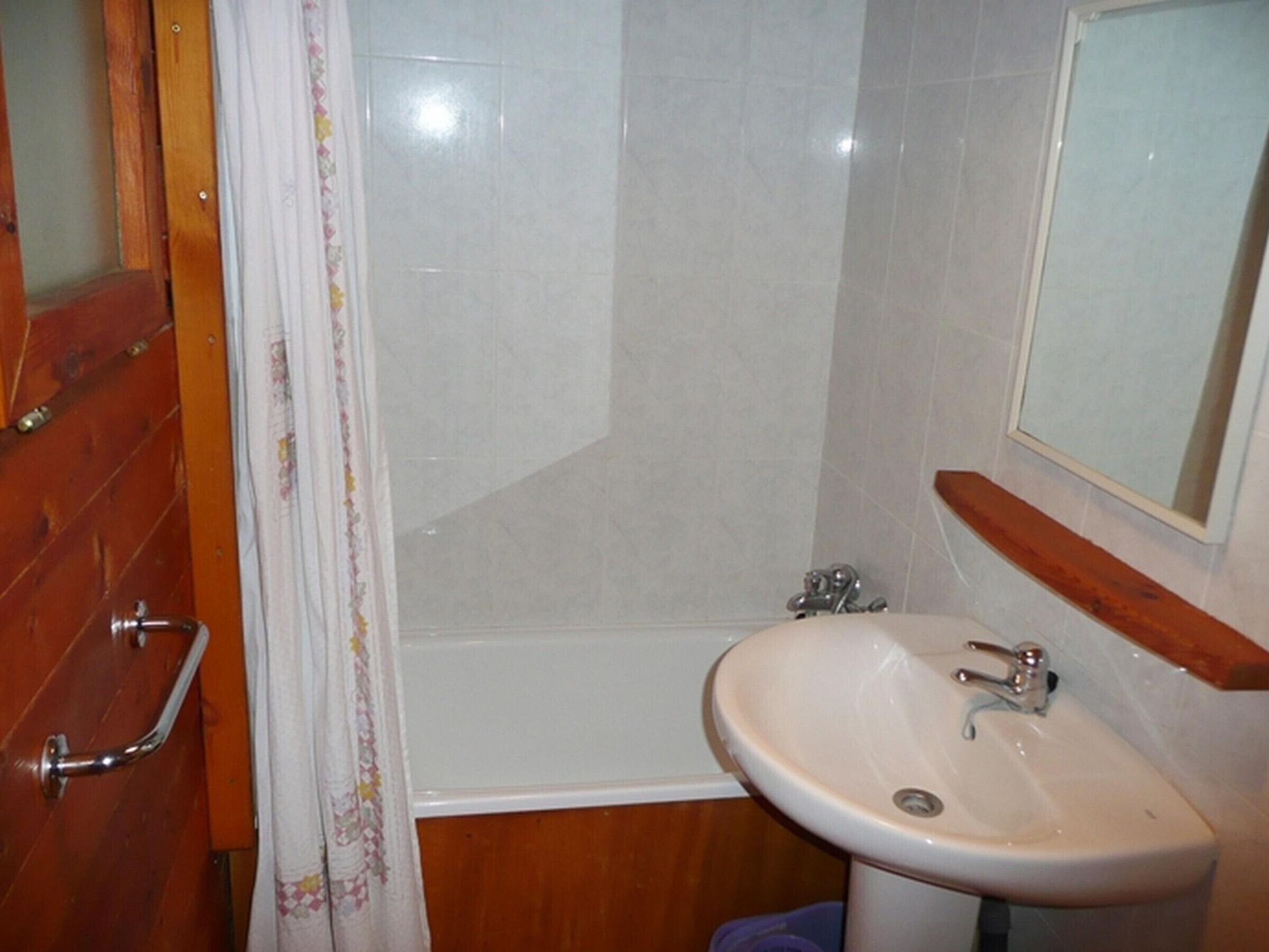 Ein Badezimmer mit einem weißen Waschbecken, einem Spiegel und einer Duschkabine.