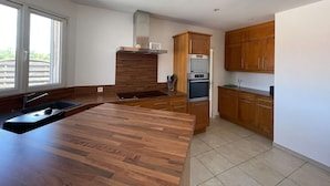 Una cocina moderna con armarios de madera, una campana extractora de acero inoxidable y una isla grande con un fregadero.