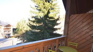 A balcony with a wooden railing, a yellow table, and a yellow chair. - Charming Apartment in Les Gets Center, 150m from Chavannes Slopes (Les Gets)