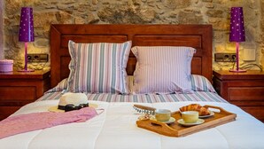 A neatly made bed with striped pillows, a wooden headboard, and a tray with croissants and cups. - Charming Rustic-Modern House with A/C & WiFi, 200m from Beach in Palamós Center (Palamós)