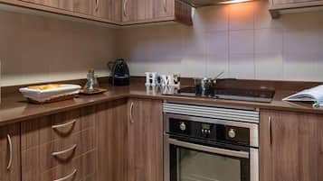 A modern kitchen with wooden cabinets, a built-in oven, a stovetop, and a coffee maker.