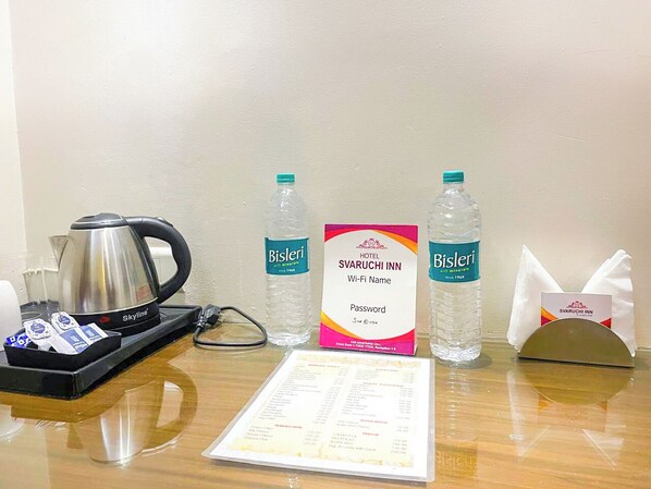 A hotel room with a coffee maker, water bottles, a Wi-Fi name and password sign, a menu, and a tissue dispenser. - Svaruchi (A Boutique Hotel) (New Delhi)