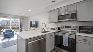 A modern kitchen with stainless steel appliances, a large island, and a view of the city. - New Listing!  Updated 1 bedroom bayside with a pool! (Ocean City)