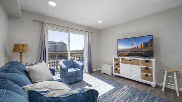 A modern living room with a sofa, armchair, and TV on a white cabinet. - New Listing!  Updated 1 bedroom bayside with a pool! (Ocean City)
