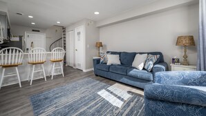 A modern living room with a blue sofa, white chairs, and a blue patterned rug. - New Listing!  Updated 1 bedroom bayside with a pool! (Ocean City)